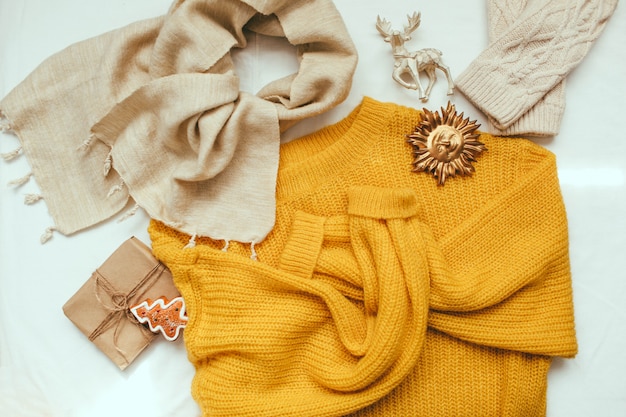 Yellow sweater, knitted mittens and Christmas decorations and gift on white background 