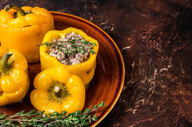 Yellow sweet bell pepper stuffed with meat, rice and vegetables. Dark background. Top view. Copy space.