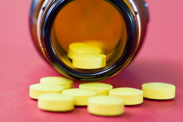 Yellow tablets lying near the glass packaging, the drug was taken out of a dark glass can to protect the drugs