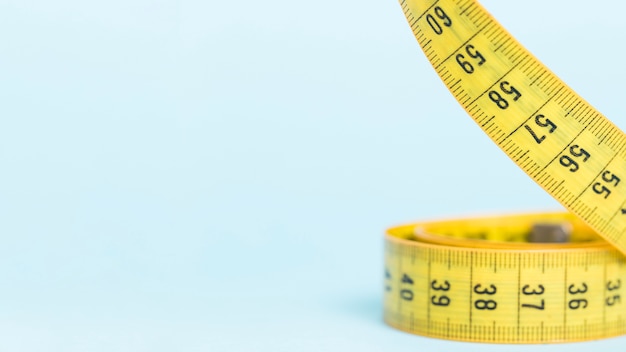 Yellow tape measure on blue background