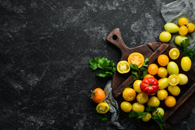 Yellow tomatoes on black stone background Top view Free space for your text