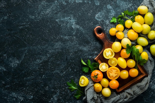 Yellow tomatoes on black stone background Top view Free space for your text