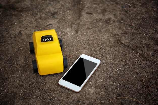 Yellow toy taxi with phone on ground