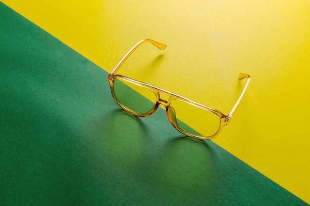 Yellow transparent sunglasses frame on anstract green diagonal background