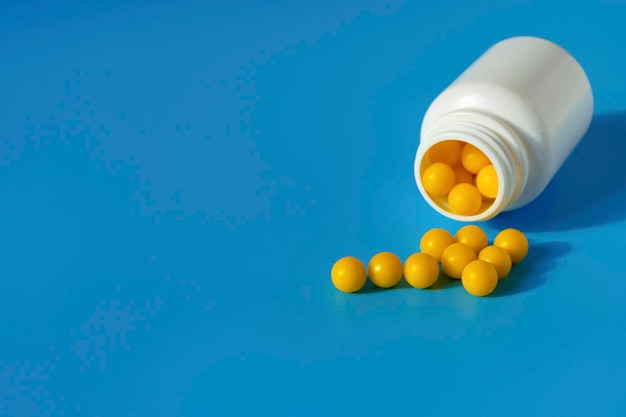 Yellow vitamins pour out from a pill bubble on a blue background Vitamin complex Multivitamins to enhance health and immunity