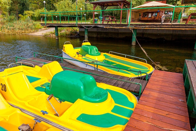 Yellow water bicycles locked at lake marina dock pier on sunny summer day