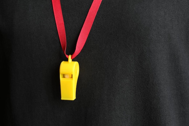 A yellow whistle with a red string hanging with the referee's shirt