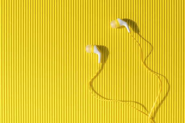 Yellow and white headphones for a smartphone on an abstract yellow background