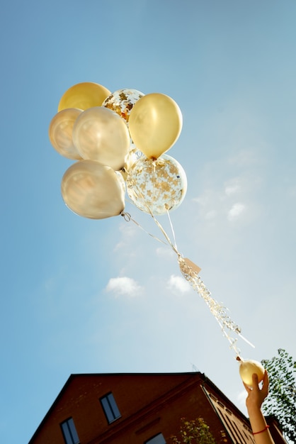 Yellow and white transparent balloons blue sky with children hands