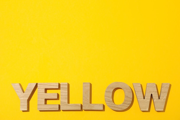 Yellow word made from wooden letters on yellow background