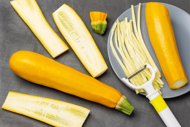 Yellow zucchini on table Striped yellow zucchini zucchini halves and vegetable cutter on gray plate