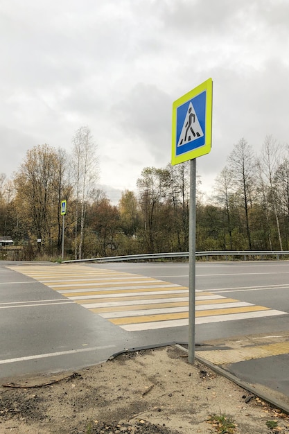 Yellowwhite painted zebra and road sign of pedestrian crossing over road