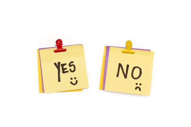 Yes and no word and happy and sad face on yellow sticky papers on a white background