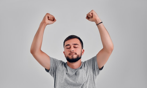 Yes! Young happy man triumphing with raised fists