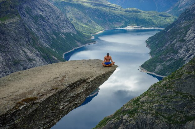 Photo yog is praying on the edge trolltunga. odda. norway