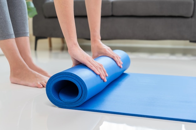 Yoga at home Young lifestyle woman rolling blue mat on floor after a workout in living room