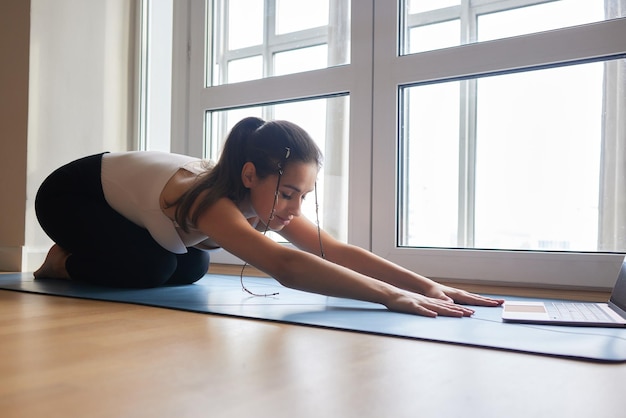 Yoga lessons online Positive yoga girl doing morning practice in front of laptop at home