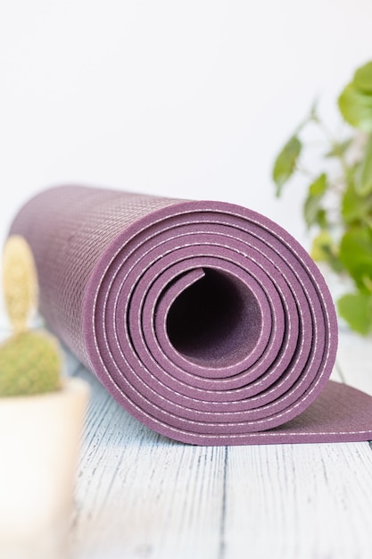 Yoga mat, bad wood beads on white wood. Essential accessories for practicing yoga and meditation.