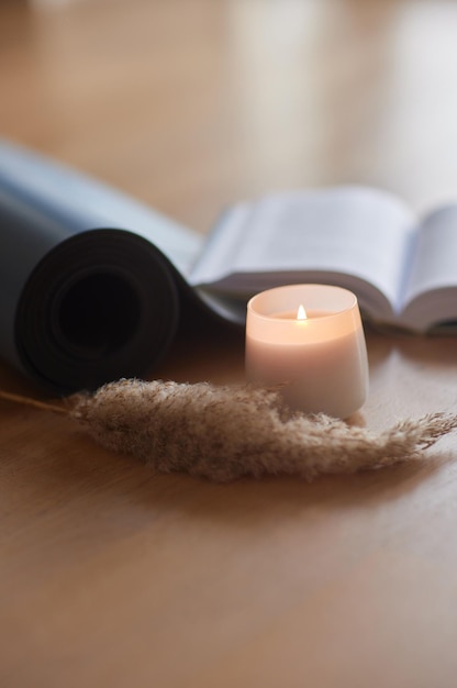 Yoga mat and burning candles on floor