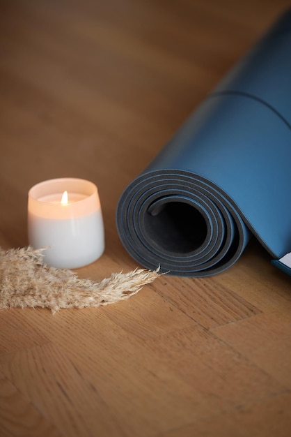 Yoga mat and burning candles on floor