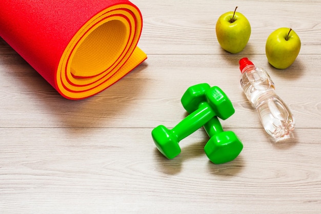 Yoga mat and different tools for fitness on floor in room