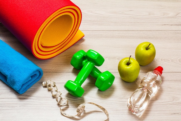 Yoga mat and different tools for fitness on floor in room