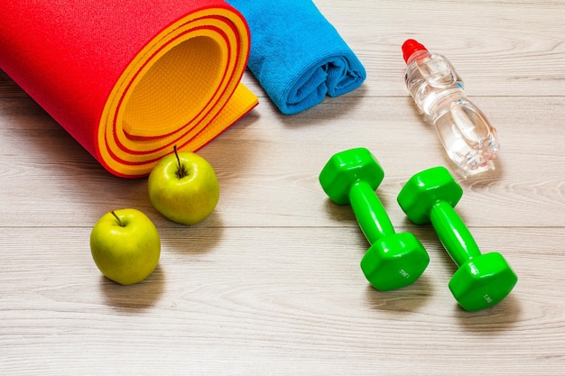 Yoga mat and different tools for fitness on floor in room