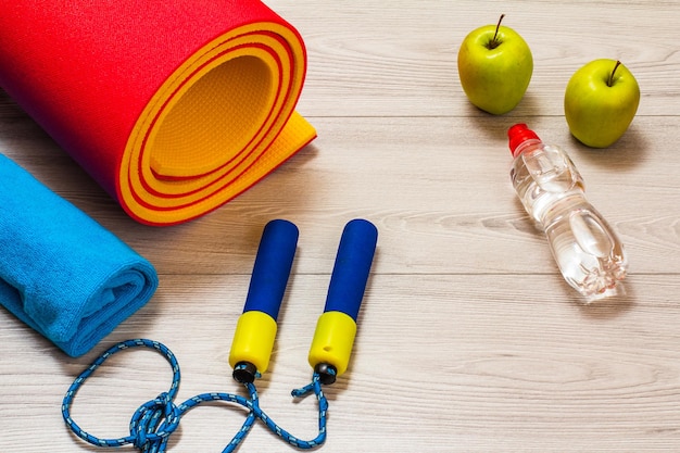 Yoga mat and different tools for fitness on floor in room