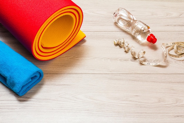 Yoga mat and different tools for fitness on floor in room