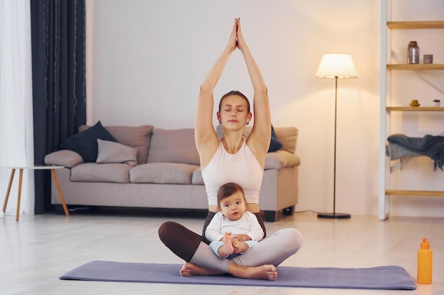 On the yoga mat Mother with her little daughter is at home together