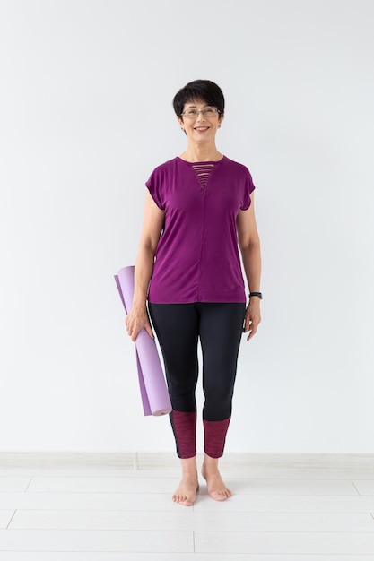 Yoga, people concept - Portrait of a middle age woman after yoga with her mat