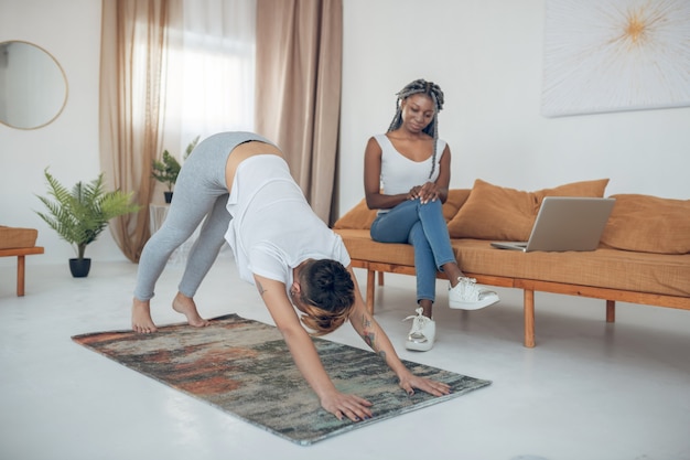 Yoga. Short-haired young girl doing yoga and standing in downward dog pose