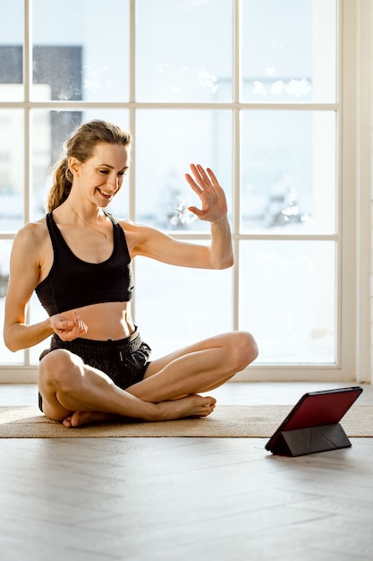 Yoga teacher conducting virtual yoga class at home on a video conference