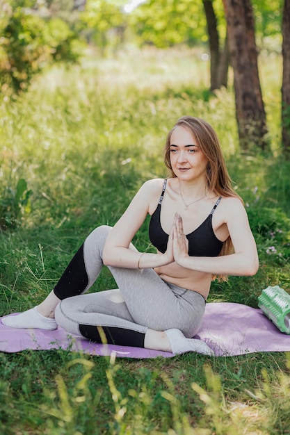 Yoga woman on green grass girl relaxes in the field Yoga woman in green park girl doing gymnastics outdoors Meditating woman in meditation in yoga pose practices outdoors