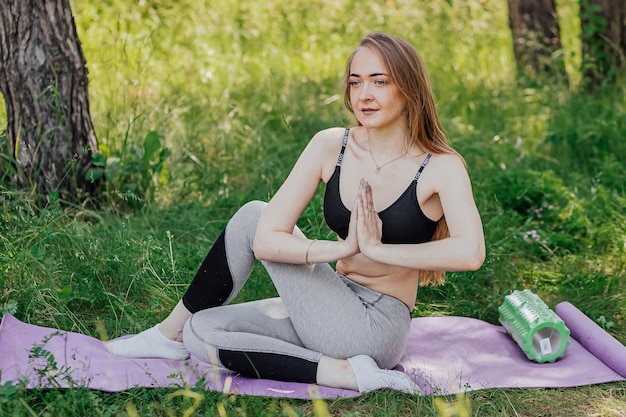 Yoga woman on green grass girl relaxes in the field Yoga woman in green park girl doing gymnastics outdoors Meditating woman in meditation in yoga pose practices outdoors