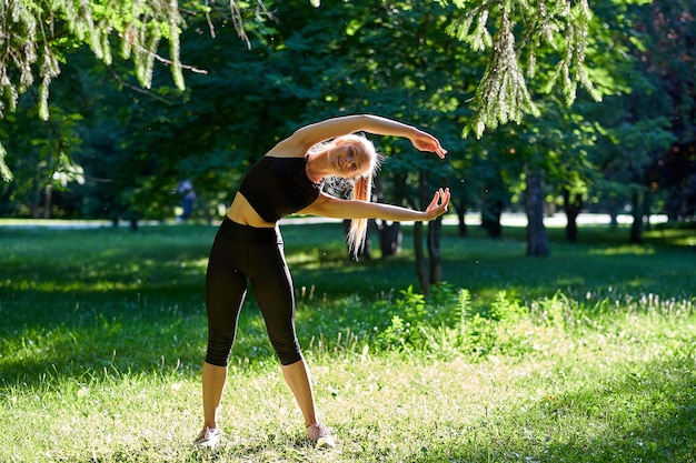 Yoga Young woman practicing yoga or dancing or stretching in nature at park Health lifestyle concept