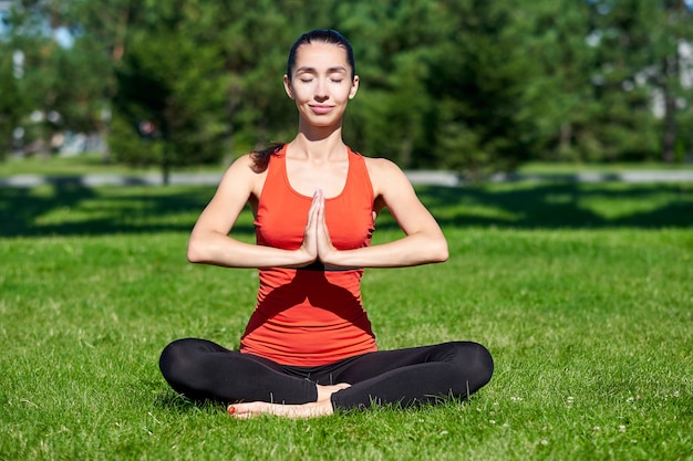 Yoga. Young woman practicing yoga meditation in nature at the park. lotus posture. Health lifestyle concept.