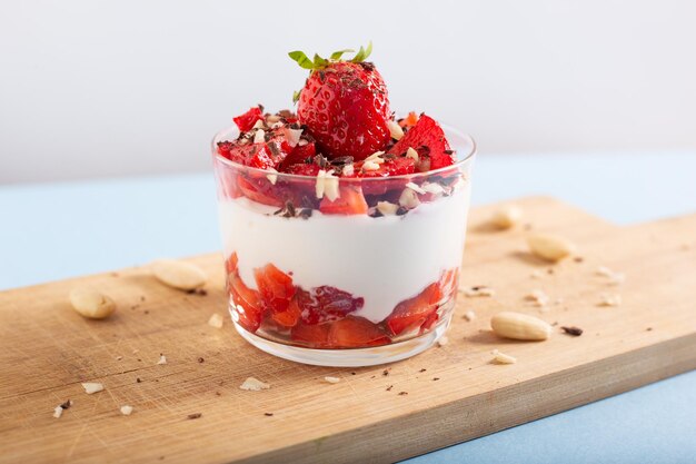 Photo yogurt cup with strawberries chocolate chips and almonds close-up of strawberries in bowl on table