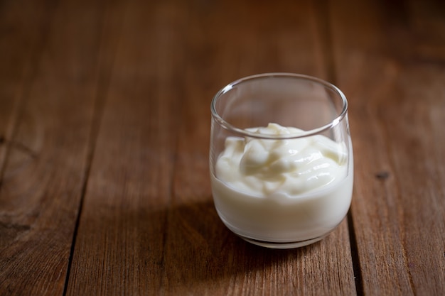 Yogurt in a glass on a brown wood table