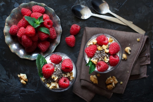 Yogurt with chia seeds, walnuts, mint and raspberries on dark close up