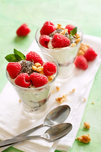 Yogurt with chia seeds, walnuts, mint and raspberries on green