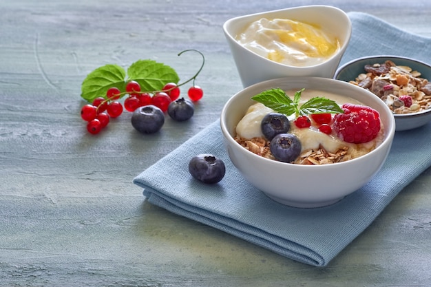 Yogurt with muesli and berries, healthy dessert on neutral background