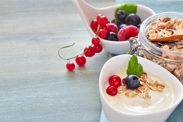 Yogurt with muesli and berries, healthy dessert on neutral surface