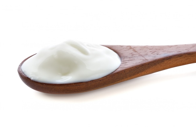 Yogurt on wooden spoon isolated on white.