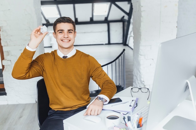 Yong brunette worker throws paper at his office during break time .