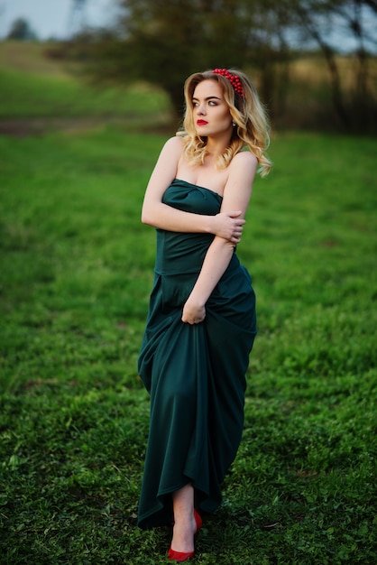 Yong elegant blonde girl at green dress on the garden in spring.