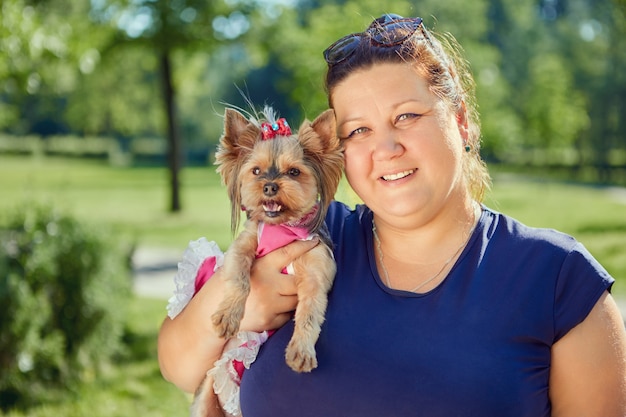 Yorkshire terrier dog in arms of fat mature woman