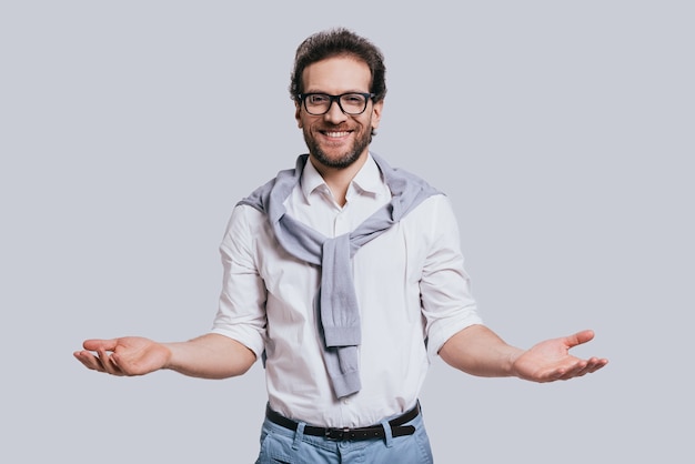 You are welcome! Handsome young man in smart casual clothes gesturing and smiling while standing 