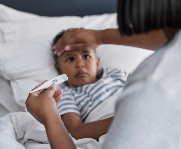 You do feel a little warm Shot of a little boy lying in bed and feeling sick while his mother checks his temperature