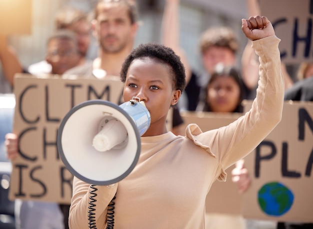 You will hear our voices. Shot of a young woman speaking through a megaphone at a protest.